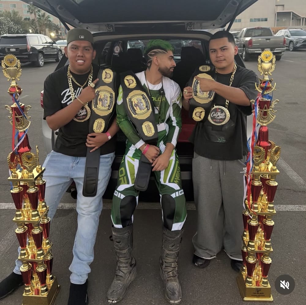 Tony y su equipo junto al modelo del color verde, con cinturones de campeón y trofeos de primer puesto